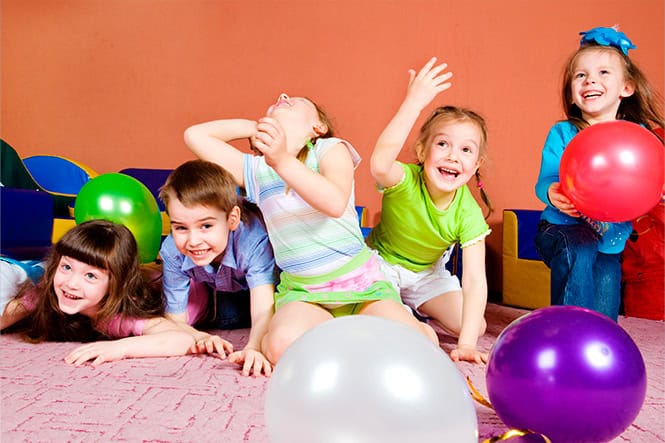 Les enfants rient et jouent avec des ballons lors d'une fête d'anniversaire