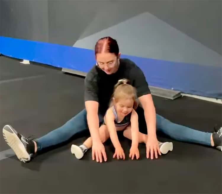 Femme et enfant faisant des exercices de gymnastique et d'étirement pour gagner en souplesse.