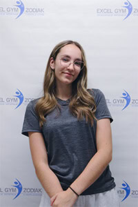 Portrait d'Amélia St-Martin, souriant devant un fond de gymnastique.