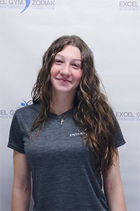 Marilou P. souriante, portant un t-shirt gris devant un fond de gymnase.