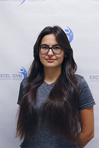 Portrait de Mayya G., souriante, devant un logo de gymnase.