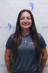 Corinne H., employée souriante, portant un t-shirt gris avec un collier.