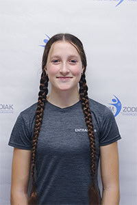 Olesya L. avec des tresses, portant un t-shirt gris.