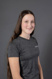 Maé-ly P. souriant, portant un t-shirt gris avec « ENTRAIN » écrit dessus.