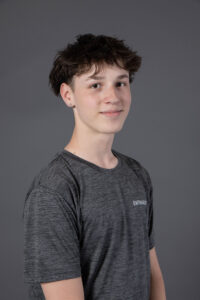 Portrait de Maé-ly P., jeune homme souriant portant un t-shirt gris