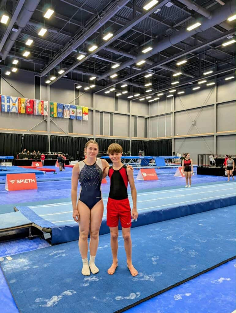 Deux jeunes athlètes de trampoline à Élite Canada 2026, souriant sur le tapis bleu.