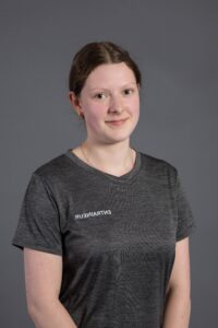 Jeune femme souriante portant un t-shirt gris avec le logo « ENTREPRISE »