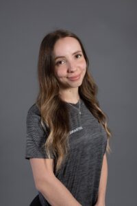 Jeune femme souriante portant un t-shirt gris avec un logo