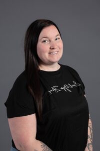 Femme souriante portant un t-shirt noir avec un logo textuel blanc